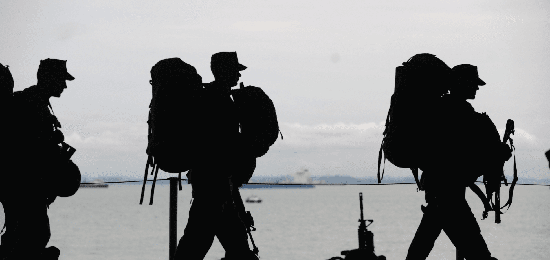 Silhouette of three army members with backpacks