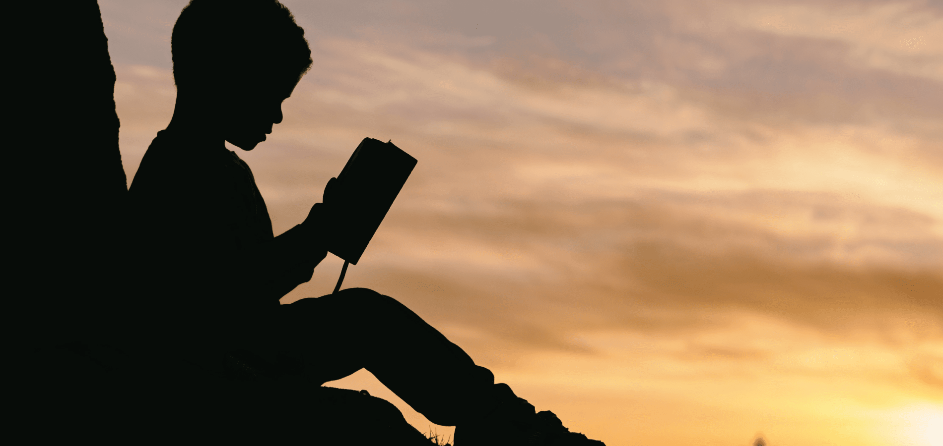 Silhouette of a child reading a book