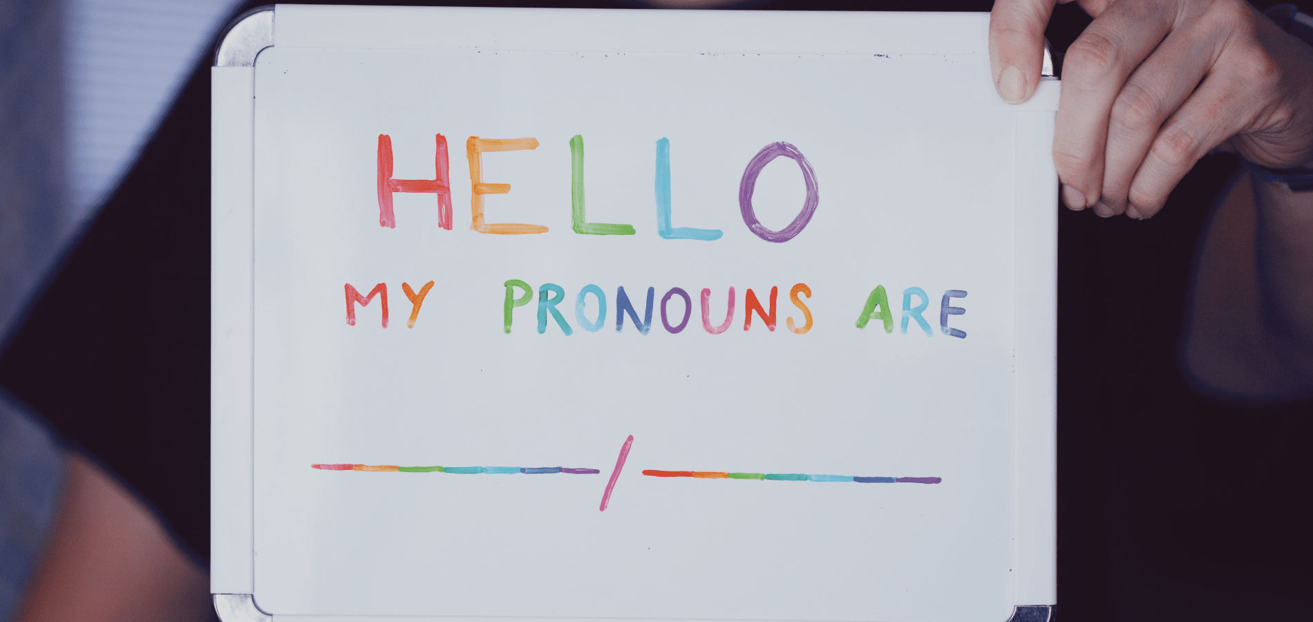 Person holding board with rainbow text