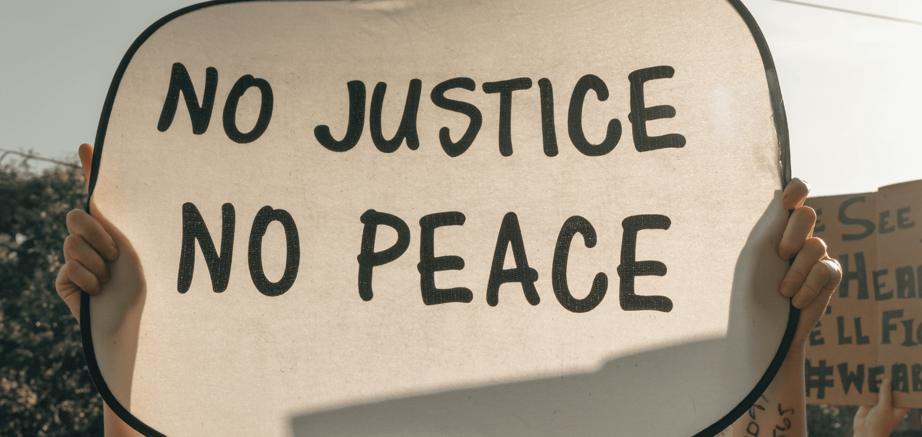 Photo of a protest sign reading "No Justice No Peace"