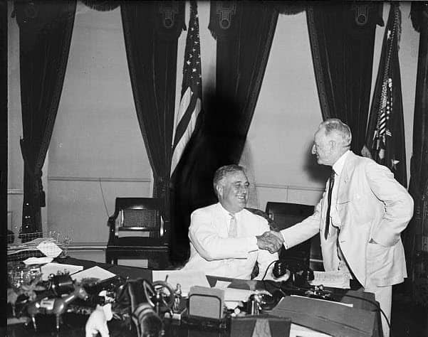 President Roosevelt and Senator Glass shake hands in the Oval Office.