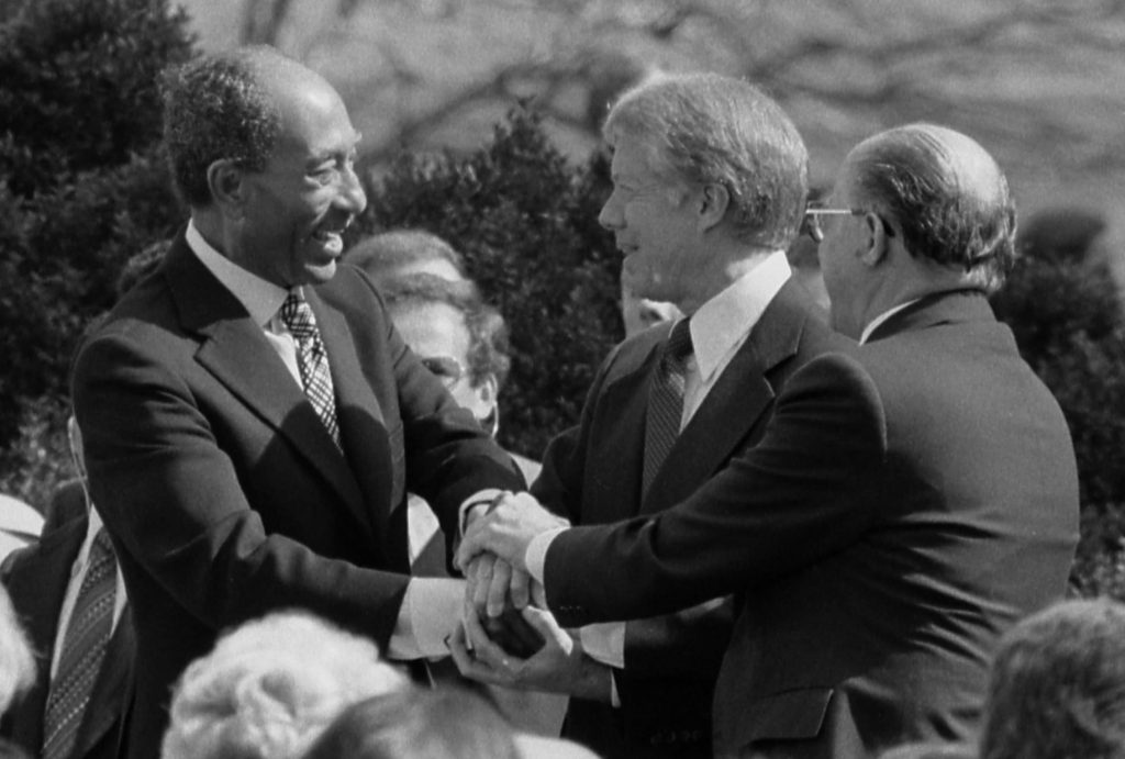 President Jimmy Carter shaking hands with Egyptian President Anwar Sadat and Israeli Prime Minister Menachem Begin at the signing of the Egyptian-Israeli Peace Treaty on the grounds of the White House.
