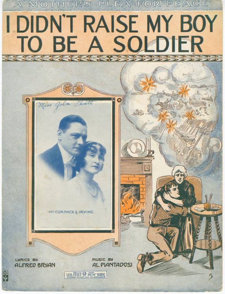 Depiction of the sheet music for the song "I Didn't Raise My Boy to Be A Soldier." A mother clutches her adult son to her breast, safe at home, while nightmarish images of young men marching off to battle hover in a cloud above their heads. A photograph of two people is foreground; presumably, they are singers.