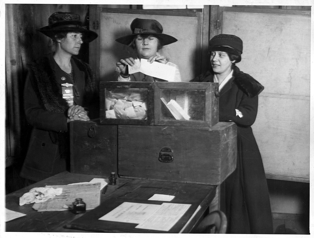 An image of women placing ballots in a ballot box