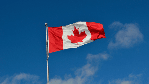 Canadian flag waving against blue sky